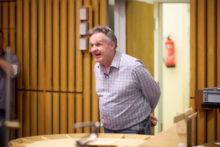 Prof. Desch at the scattering board, which is an analogy to scattering experiments in particle physics. Fast, small particles, such as electrons, can be used to explore the shape of an invisible target, e.g. a proton.